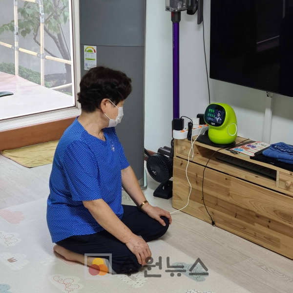 연무동에 거주하는 한 어르신이 거실에 설치한 ‘AI 케어로봇 시니어’를 살펴보고 있다.